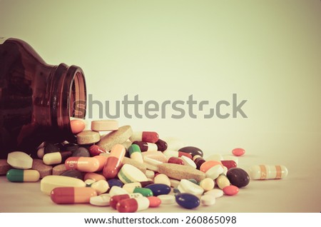 Many type of medical drugs pills capsules and medicine poring from the bottle with isolation background in vintage retro color. Used for manufacturing health industry concept.