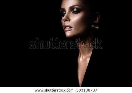 the sexy strict woman with makeup and a fashionable hairstyle poses in studio on black background