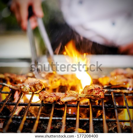 chef grilling lamb ribs on flame - stock photo