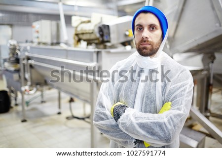 Serious young staff of seafood production factory looking at camera by workplace