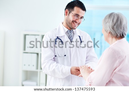 Confident doctor looking at his senior patient while speaking to her