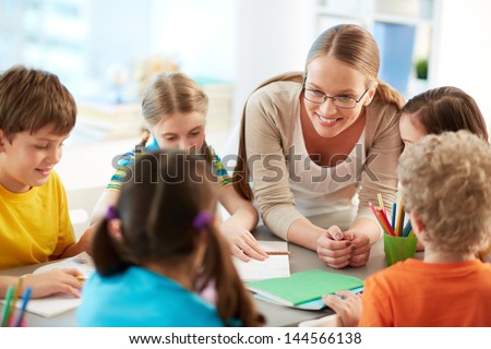 Portrait of diligent schoolkids and their teacher talking at lesson