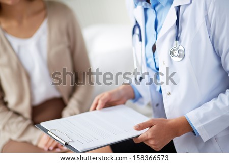 Female doctor holding application form while consulting patient