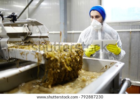 Young worker of seafood processing plant controling process of seaweed salad preparation