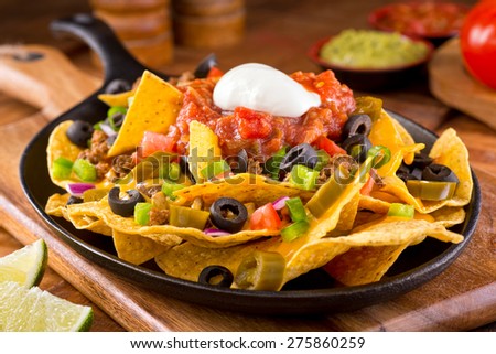 https://thumb1.shutterstock.com/display_pic_with_logo/91533/275860259/stock-photo-a-plate-of-delicious-tortilla-nachos-with-melted-cheese-sauce-ground-beef-jalapeno-peppers-red-275860259.jpg