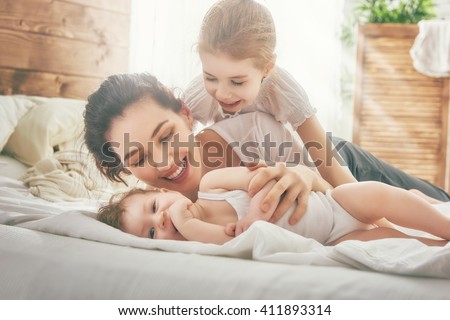 Happy loving family. Mother and her daughters children girls playing and hugging.