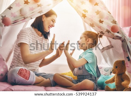 Happy loving family. Mother and her daughter girl play in children room. Funny mom and lovely child having fun indoors.