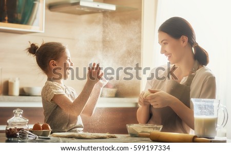 Happy loving family are preparing bakery together. Mother and child daughter girl are cooking cookies and having fun in the kitchen. Homemade food and little helper.