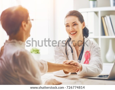 Pink ribbon for breast cancer awareness. Female patient listening to doctor in medical office. Raising knowledge on people living with tumor illness.