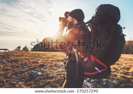 Man photographer with big backpack and camera taking photo of sunset mountains Travel Lifestyle hobby concept adventure active vacations outdoor