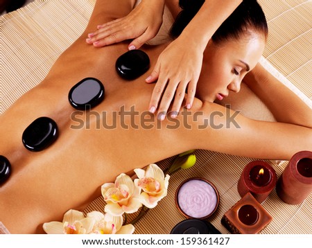 Adult woman having hot stone massage in spa salon. Beauty treatment concept.