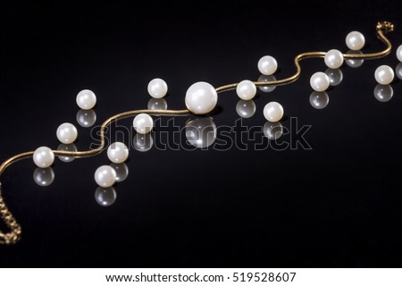 White pearls necklace on black background. Focus on the big pearl!