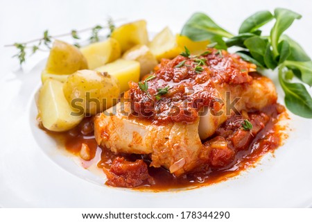 Plate of Cod or Pollack Fish Fillet Stewed in Tomato and Thyme Sauce Garnished with Boiled New Potatoes