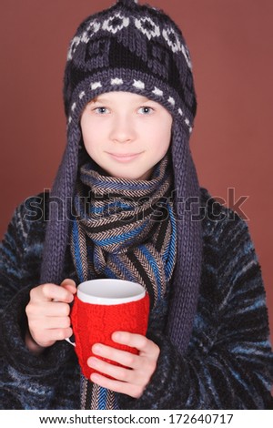 Kid boy wearing winter clothes, holding knitted cup