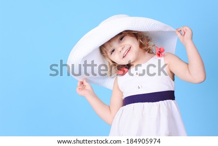 Pretty little girl holding summer hat on blue