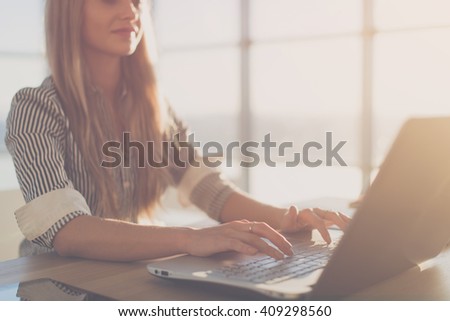 Female writer typing using laptop keyboard at her workplace in the morning. Woman writing blogs online, side view close-up picture.