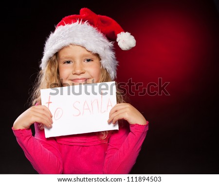 Child with letter to Santa Claus. Little girl in christmas hat on black background