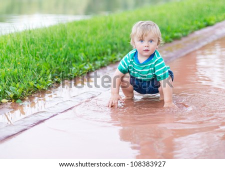 Child playing in a puddle after rain