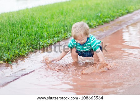 Child playing in a puddle after rain