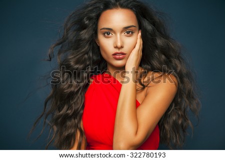 người phụ nữ thanh lịch với mái tóc lượn sóng dài và đôi môi đỏ mặc váy đỏ. Thời trang và mỹ phẩm phòng thu shot, ngang