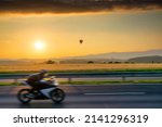 Landscape with hot air balloon and motion blurred motorcycle at sunset