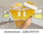 Small photo of Before and After of Man Using A Paint Roller to Reveal Newly Remodeled Room with Fresh Yellow Paint, Coffered Ceiling and New Floors.