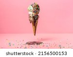 Small photo of funny creative concept of flying wafer cone with ice cream covered, strewed sprinkles and poured with chocolate icing on pink background