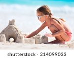 Small photo of Little girl at tropical beach making sand castle