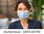 Small photo of Portrait of happy young woman wearing face medical mask. Hopeful girl with protective face mask looking at camera. Smiling woman wearing safety protective mask to fight against covid-19 pandemic.