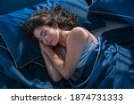 Small photo of Top view of young beautiful woman dreaming in bed and relaxing at night. High angle view of woman with closed eyes sleeping well at home in the dark. Beautiful girl sleeping peacefully under late.
