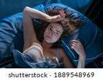 Small photo of Stressed woman on bed late at night suffering from insomnia, sleep apnea or stress. Top view of depressed girl lying in bed late at night. High angle view of awake girl in the middle of the night.