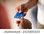 Small photo of Close up hands of a black woman giving bank credit card to man. Detail shot of a woman passing a payment credit card to the seller. Hand of african american man receiving payment from customer.