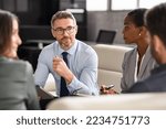 Small photo of Successful businessman discussing strategy with partners in meeting room. Mature business man entrepreneur in conversation with team in office. Businessman explaining new business ideas to peers.