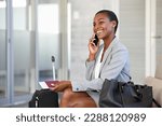 Small photo of Smiling african businesswoman sitting in waiting room and talking over smartphone. Mature black woman traveller talking on cell phone at airport lounge. Successful woman on mobile phone at terminal.