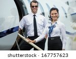 Portrait of happy confident airhostess and pilot standing on private jet's ladder