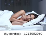 Small photo of Serious insomniac woman looking at camera lying on the bed in the night at home