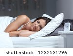 Small photo of Angry insomniac woman looking at camera lying on a bed in the night at home