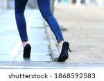 Small photo of Back view close up of a woman legs with high heels stumbling in the street