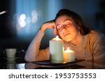 Relaxed woman smelling aromatic candles in the night in the living room at home