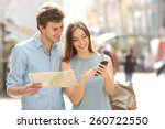 Couple of tourists consulting a city guide and smartphone gps in the street searching locations