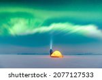 Small photo of Tourist with flashlight near yellow tent lighted from the inside against the backdrop of incredible starry sky with Aurora borealis. Amazing night landscape. Northern lights in winter field
