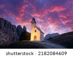 Incredible view on small iIlluminated chapel - Kapelle Ciapela on Gardena Pass, Italian Dolomites mountains. Colorful sunset in Dolomite Alps, Italy. Landscape photography