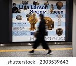 Small photo of TOKYO, JAPAN - May 13, 2023: Person passes an advert in a Tokyo Metro subway station for a Lisa Larson exhibition at Matsuya Ginza Department Store.