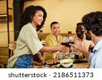 Small photo of A group of tipsy friends toasts with red wine during a dinner party at a restaurant.