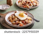 Small photo of Corned beef hash with potatoes, cabbage and carrot on a plate topped with a fried egg