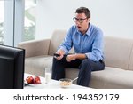 Man having breakfast while watching something shocking on tv