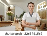 Small photo of Portrait of smiling spa salon receptionist holding folder