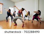Group of energetic hip-hop dancers focused on training while gathered together in spacious dance hall
