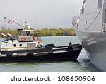 PEARL HARBOR, HAWAII - AUGUST 2010: A Tugboat in Pearl Harbor pulls a Japanese Destroyer out to sea for RIMPAC exercises on August 3, 2010.