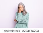Small photo of middle age gray hair woman looking stressed, ashamed or upset, with a headache, covering face with hand